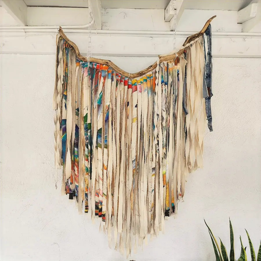 A wall hanging of long painted strips hung from a branch