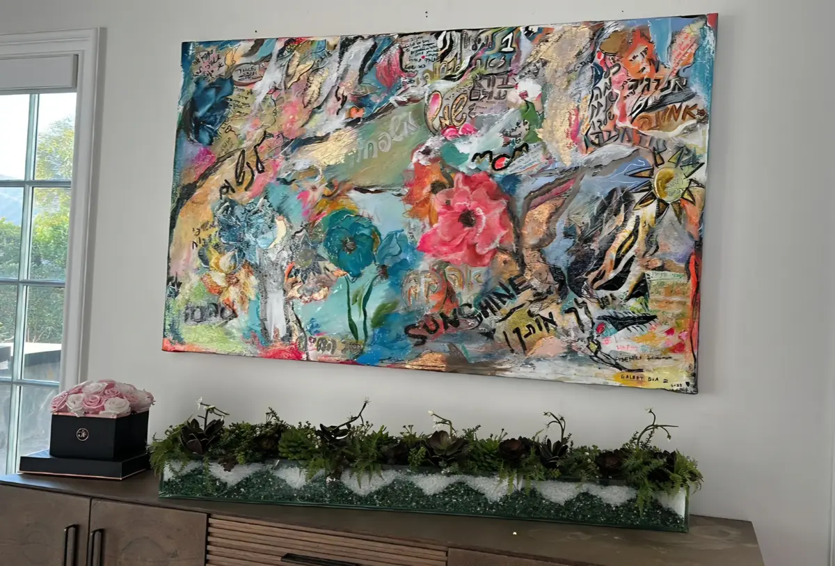A colorful birthday canvas full of guests’ wishes, hanging above a sideboard in a home